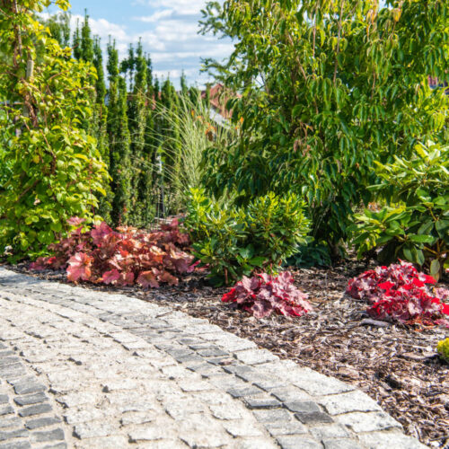 Beautiful Residential Backyard Garden with Granite Bricks Path. Summer Time Garden Scenery.