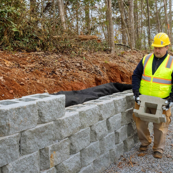 In part of construction project that is building retaining walls on new site contractor installing concrete block walls