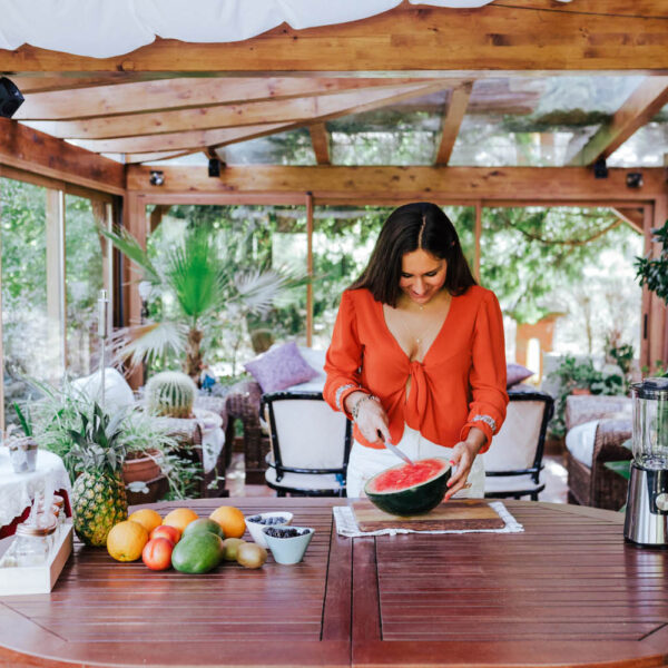 young woman preparing a healthy recipe of diverse fruits, watermelon, orange and blackberries. Using a mixer. Homemade, indoors, healthy lifestyle