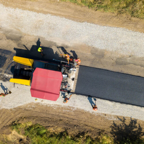 Aerial view of new road construction with asphalt laying machinery at work.