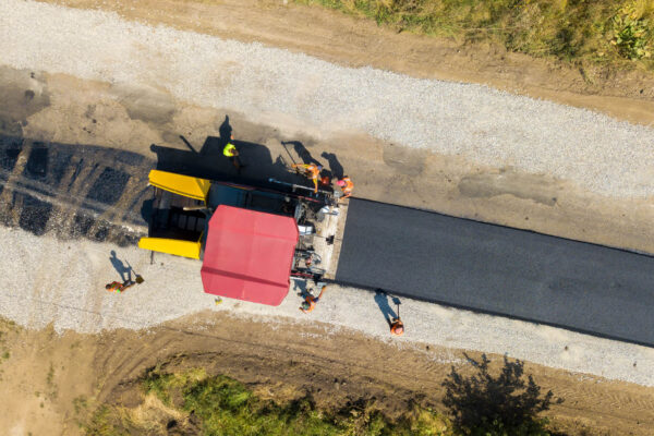 Aerial view of new road construction with asphalt laying machinery at work.