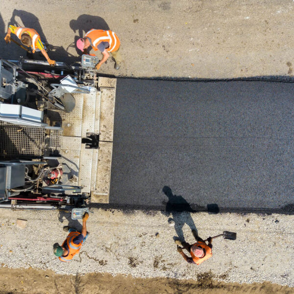 Aerial view of new road construction with asphalt laying machinery at work.