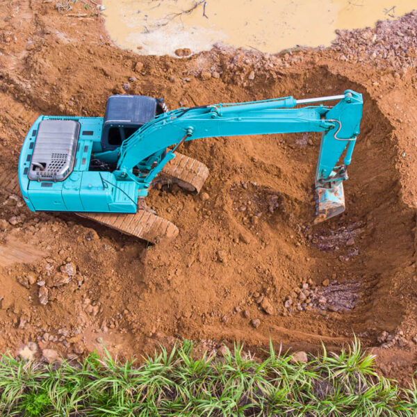 Backhoe loading soil into a truck then the truck carries soil for sale.