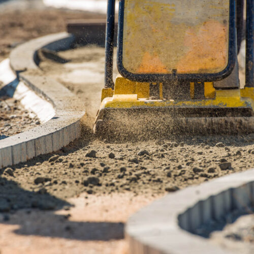 Plate Compactor in Action. Compacting Soil For a Brick Pavement.