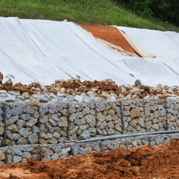 Series of close-up slope retention construction design with rocks and mesh to manage landslide in residential area